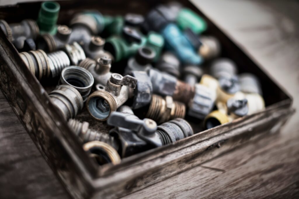 Washers and hose pipe joint fittings in a wooden box in the greenhouse.